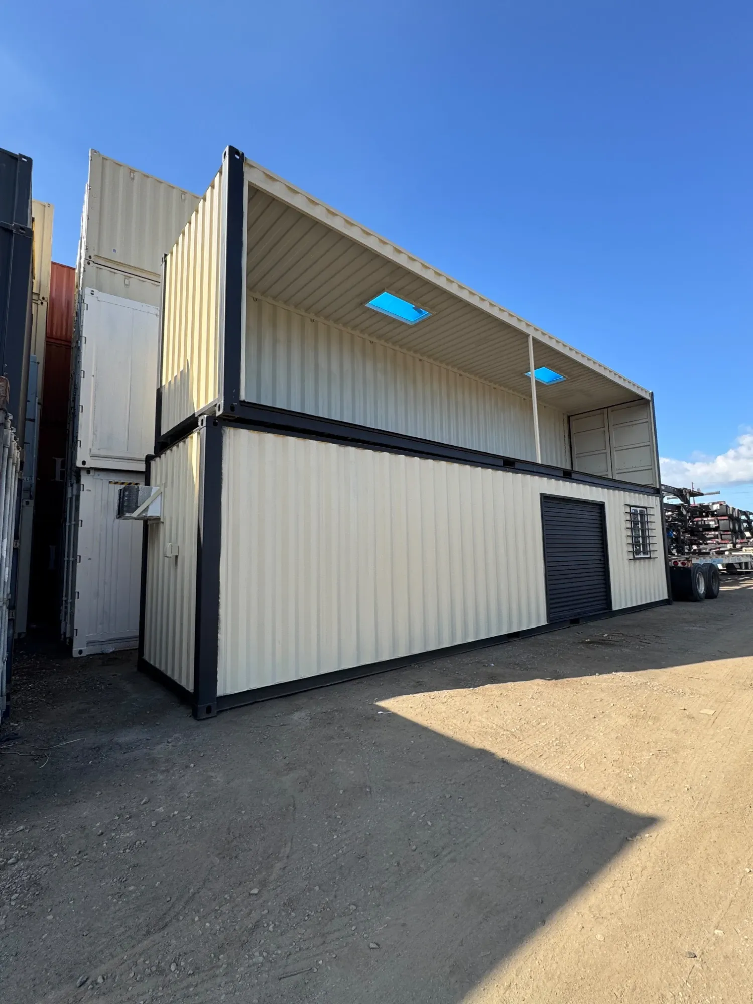 Two-story container build with a roll-up door, window and covered deck